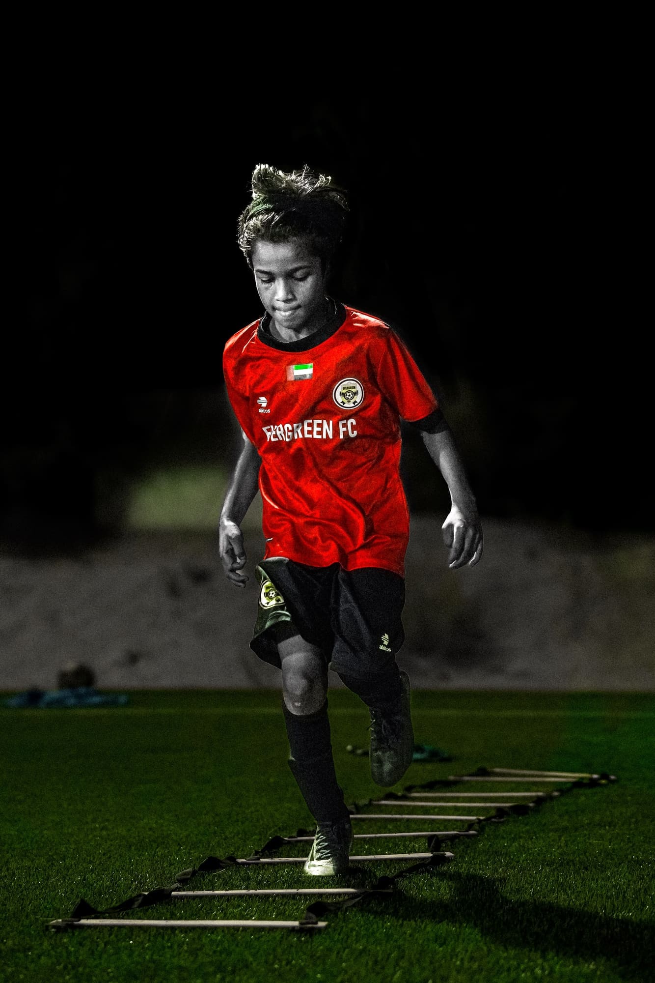 Player running an agility ladder under stadium floodlights