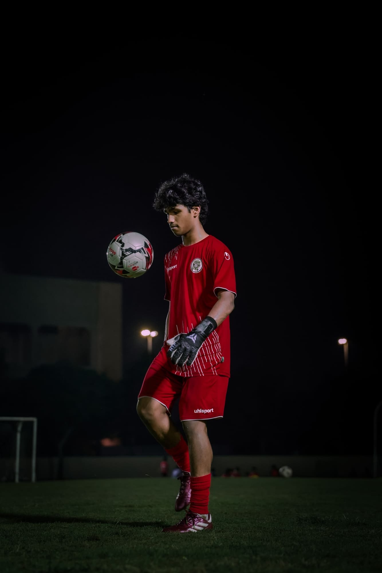 Player in red kit controlling a ball at night