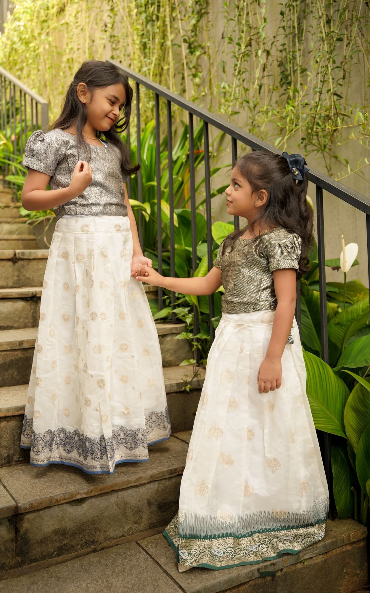 Two sisters in traditional dress on a garden stairway